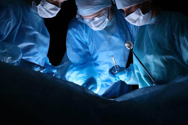 Surgeons in blue scrubs and masks during a medical operation.